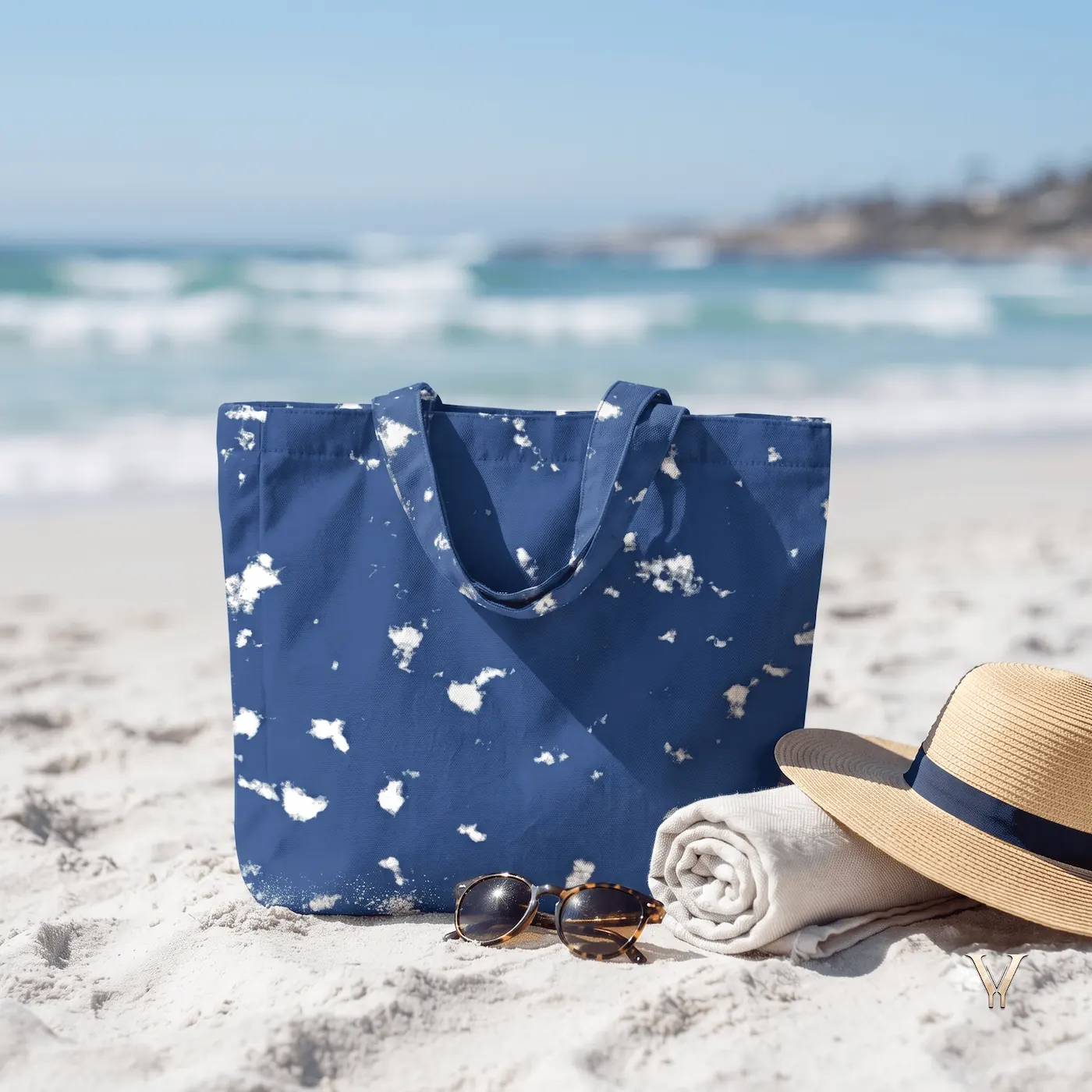 Oceanic Mist AOP Designer Large Tote Bag by VertexVault Studio on white beach sand, showing a deep blue ocean-inspired pattern bag next to a straw hat, sunglasses, and a rolled towel with waves in the background.